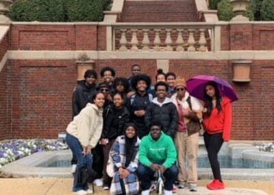 MKYF A group of people posing for a photo on steps outdoors with some holding an umbrella.
