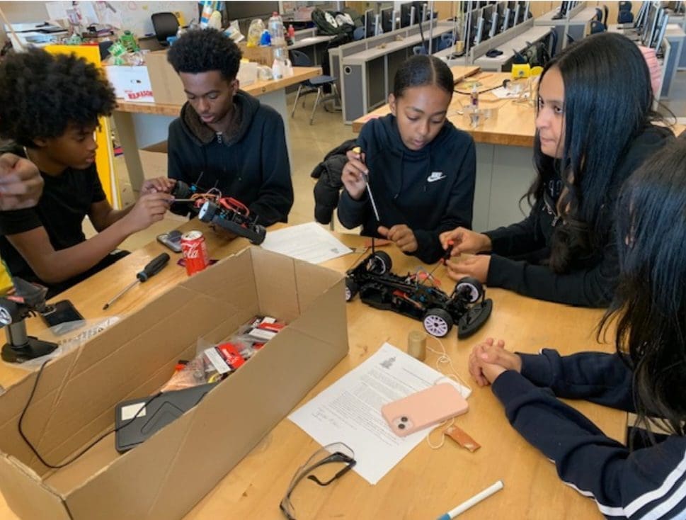 MKYF Students engaged in assembling and discussing robotic projects.