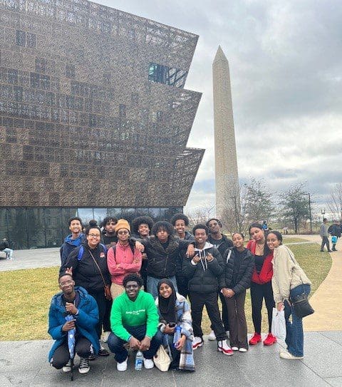 MKYF Group of people posing for a photo with the national museum of african american history and culture and the washington monument in the background.