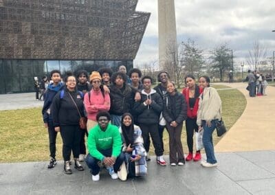 MKYF Group of people posing for a photo in front of the national museum of african american history and culture with the washington monument in the background.