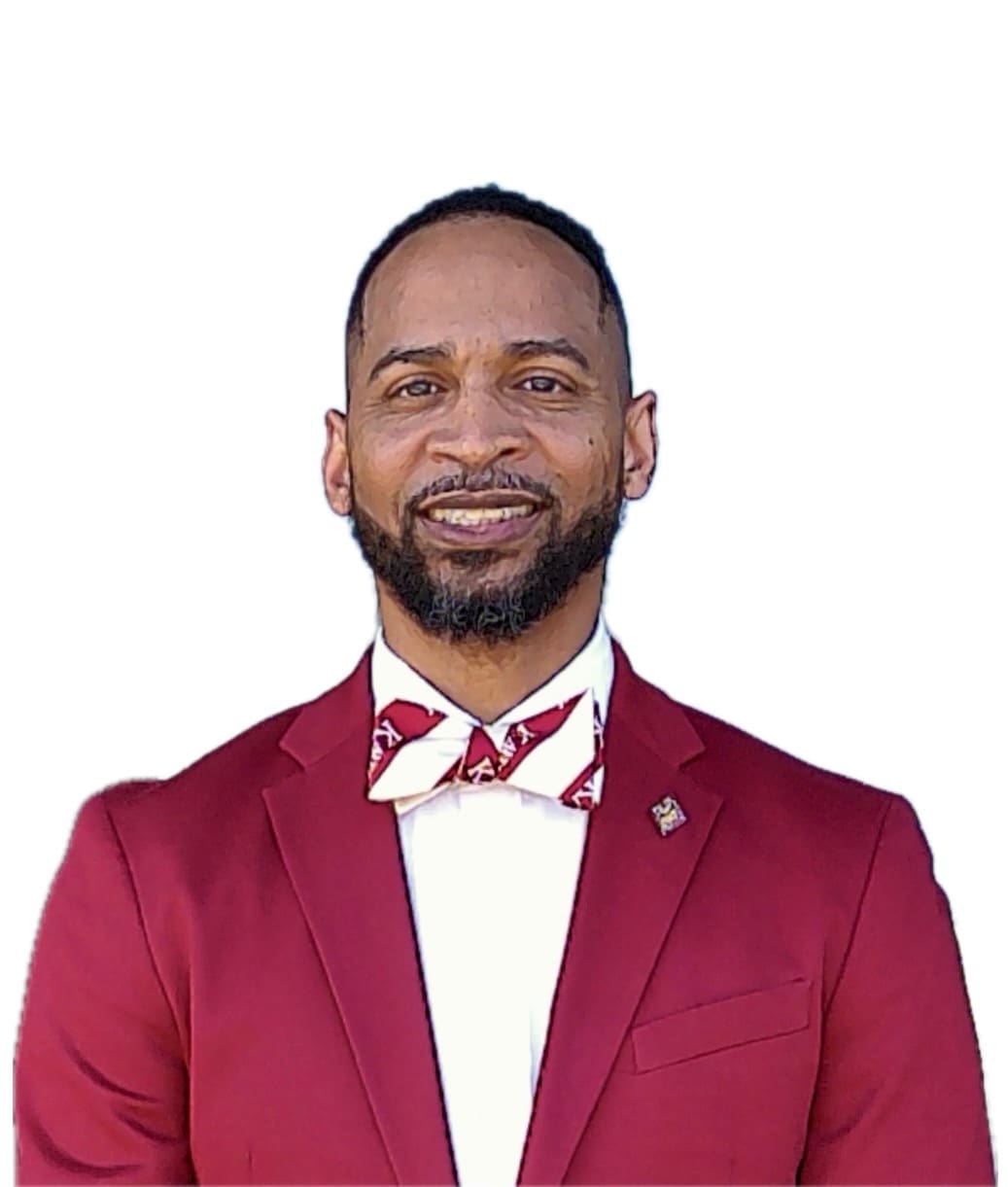 MKYF A man in a maroon suit and patterned bow tie smiles at the camera against a plain white background.